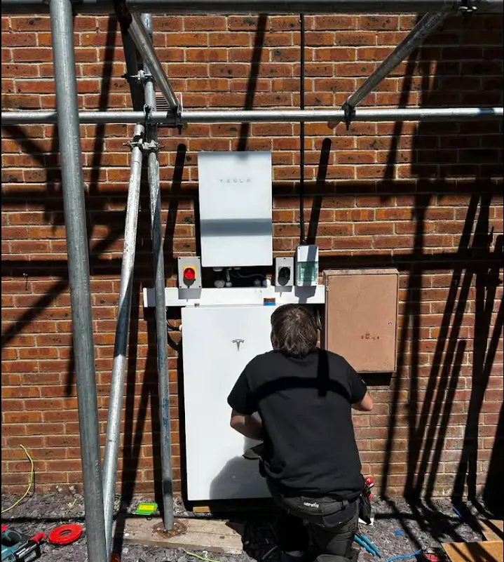 Technician installing Tesla battery on brick wall