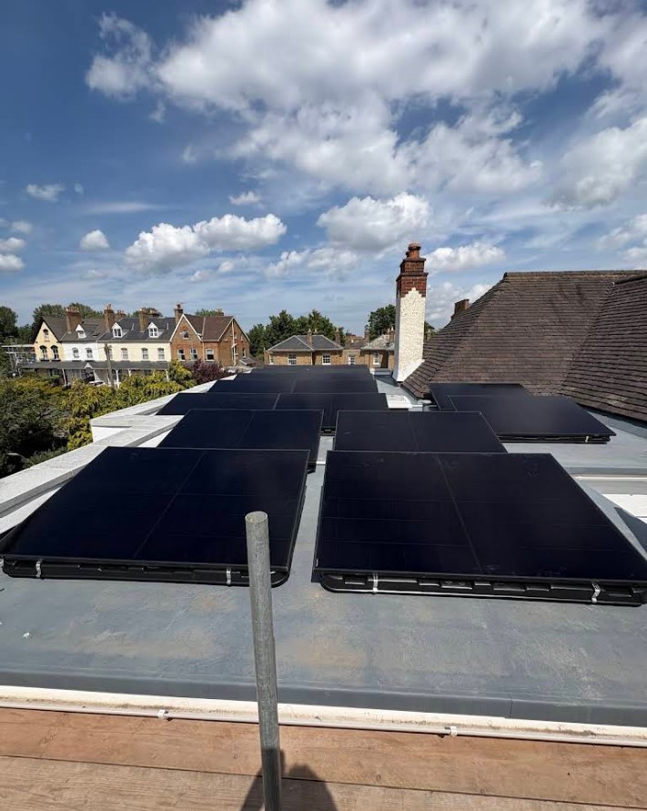 Solar panels on rooftop under blue sky with clouds.